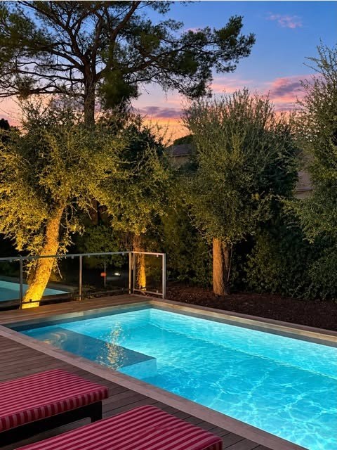Publication Instagram : piscine éclairée au coucher du soleil avec terrasse en bois